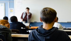 Junge in schwarzem Kapuzenpullover in einer Schule