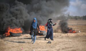 Zwei verschleierte Frauen in Gaza vor brennenden Reifen